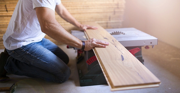 flooring installer cuts a piece of hardwood flooring